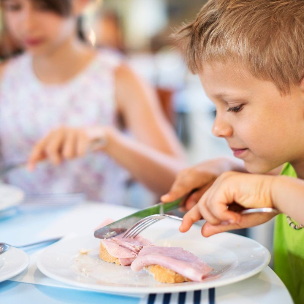 Niño comiendo jamón cocido en una tostada